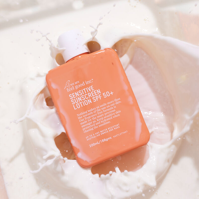Orange bottle of sensitive sunscreen lotion with text on a white background