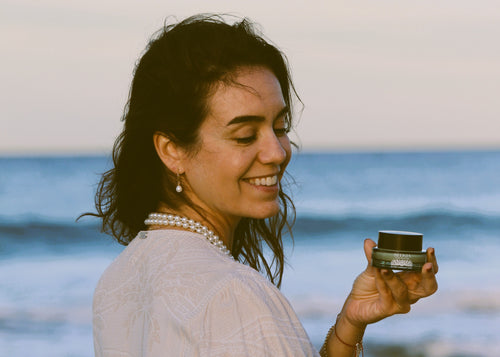 Woman holding a jar on a beach with ocean in the background